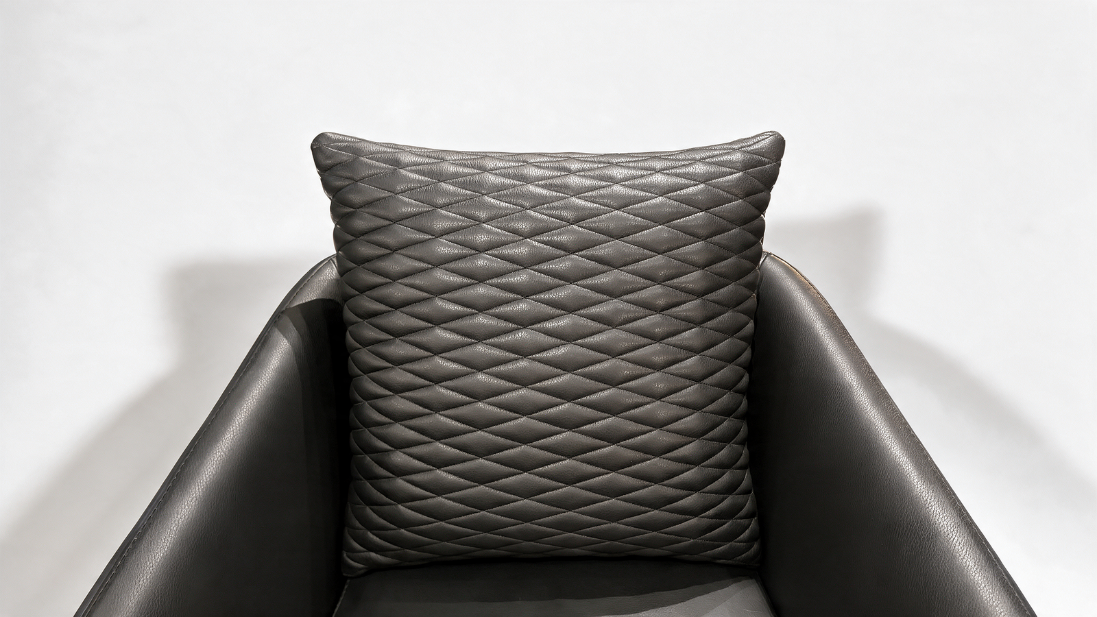 Quilted cushion on black faux leather armchair seat