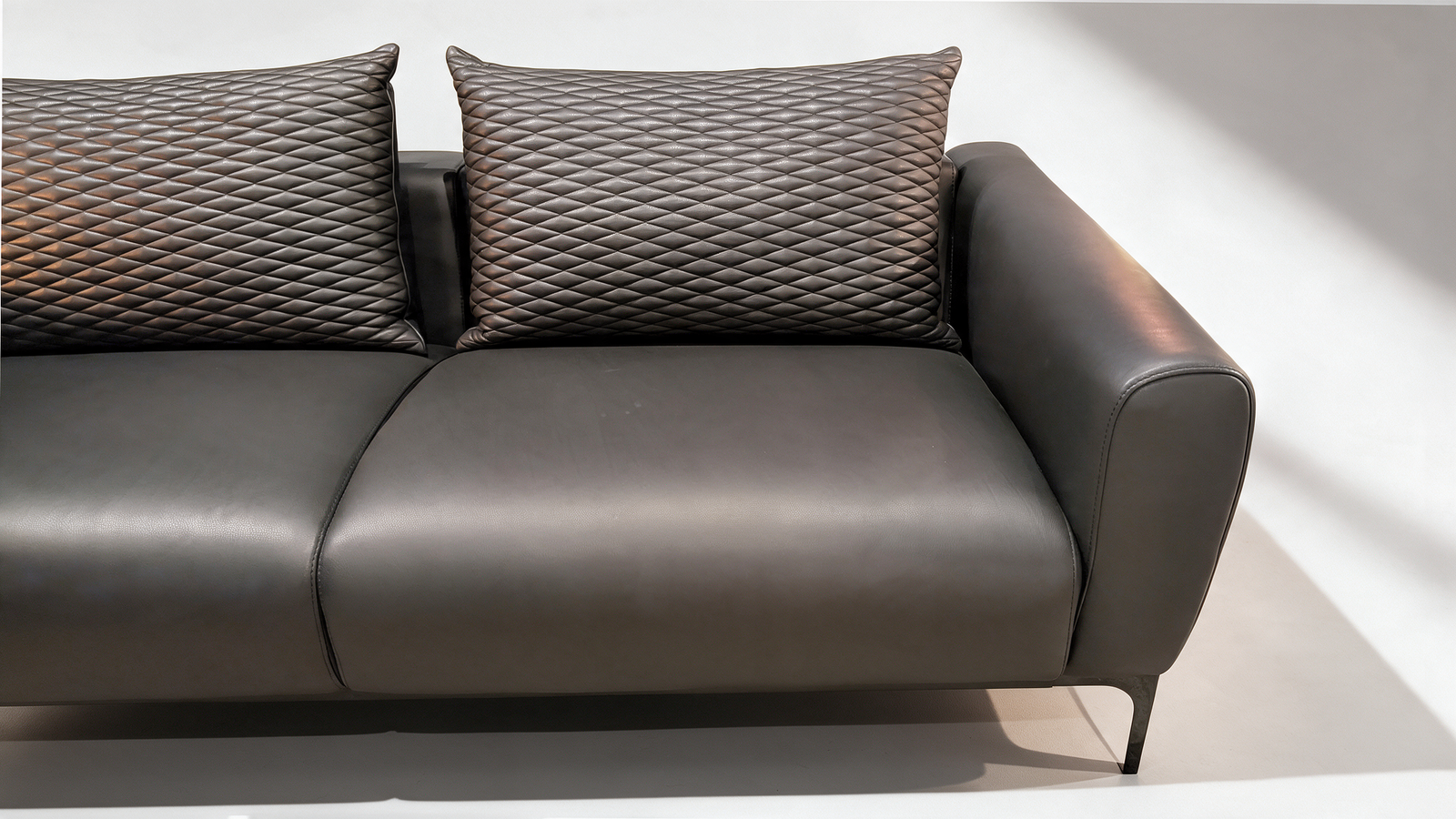 Black faux leather two seater sofa with quilted scatter cushions