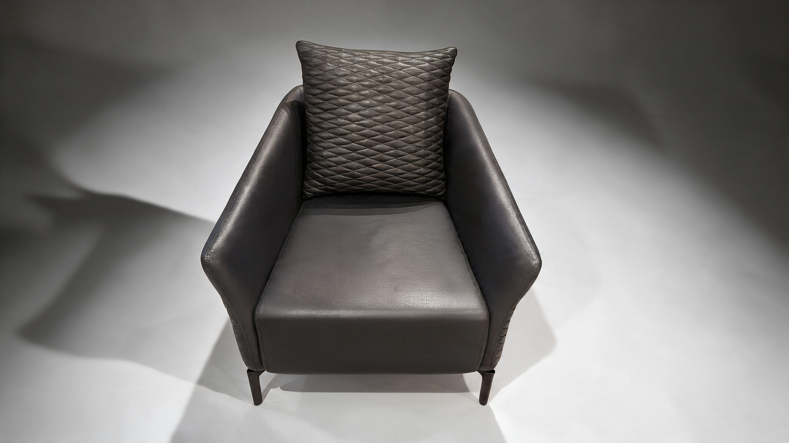 Black faux leather armchair with quilted scatter cushion