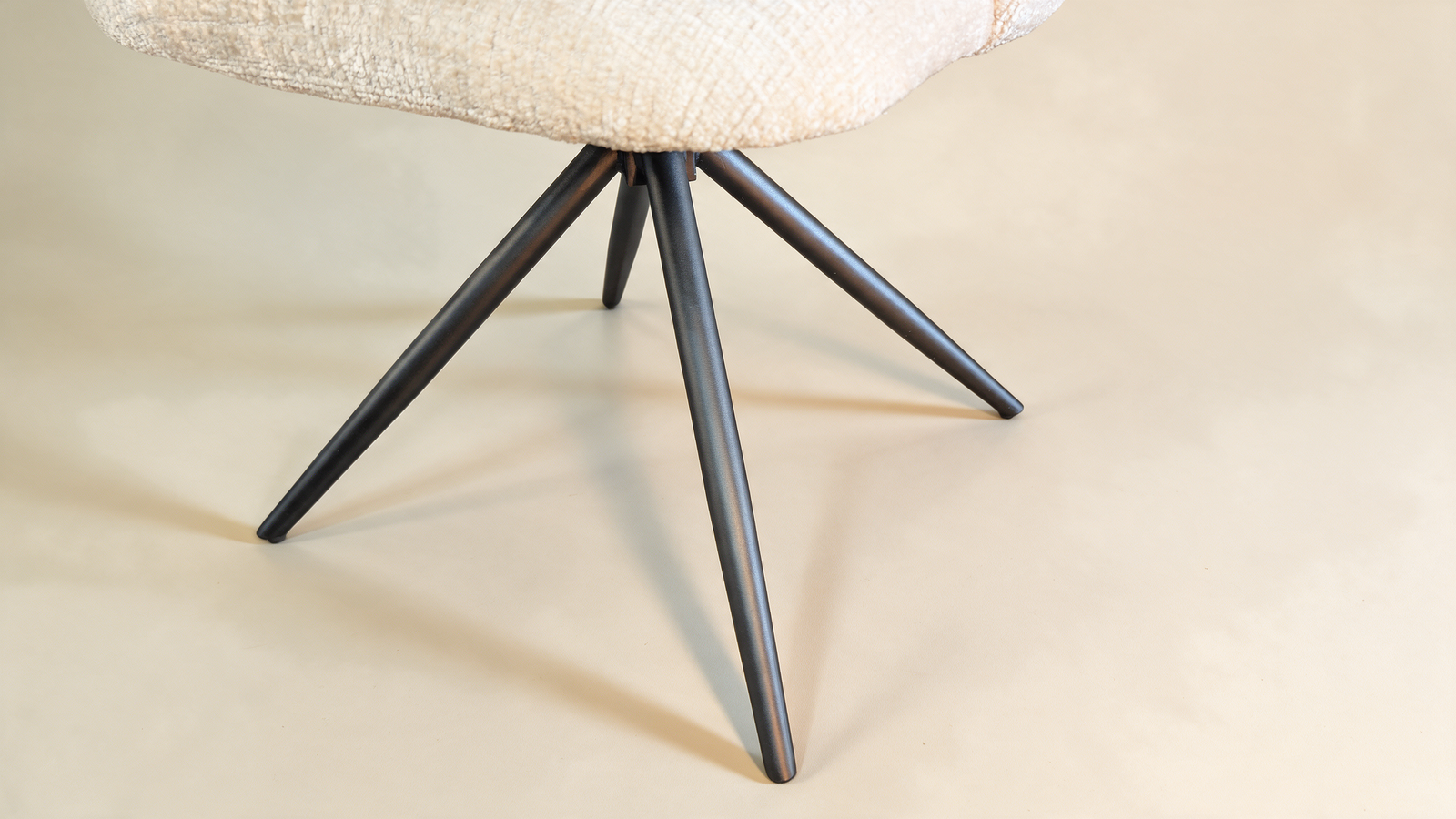 Boucle swivel accent chair with cut-out back, close-up of black metal swivel base