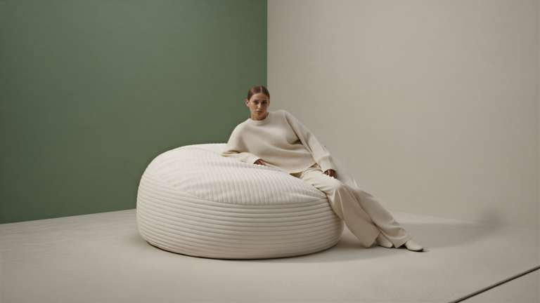 Person relaxing on a large cream faux fur bean bag in a studio