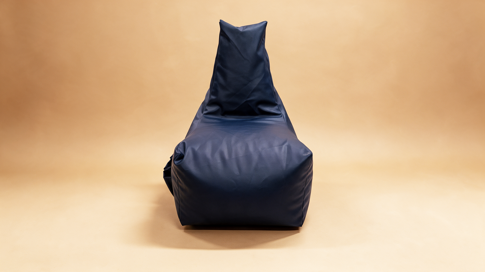 Navy bean bag lounger chair on a warm camel backdrop